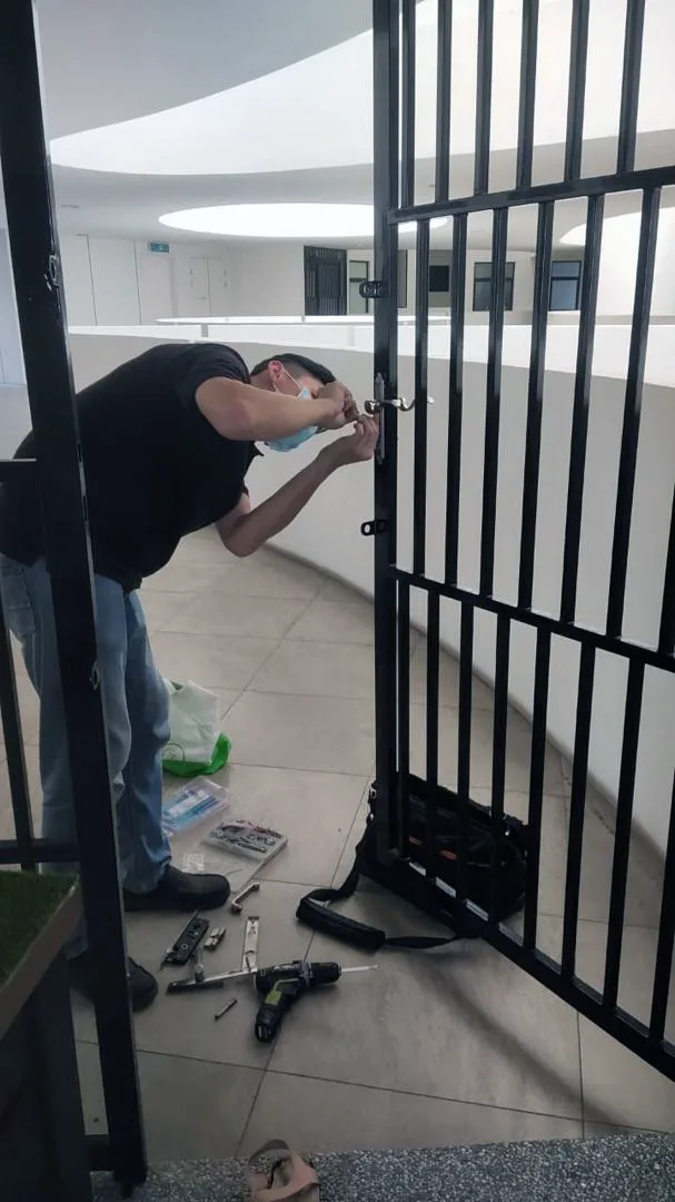 MyLock-verified technician installing a keypad smart lock on a metal grille gate in Puchong