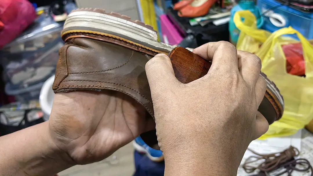 Hands repairing the sole of a leather shoe