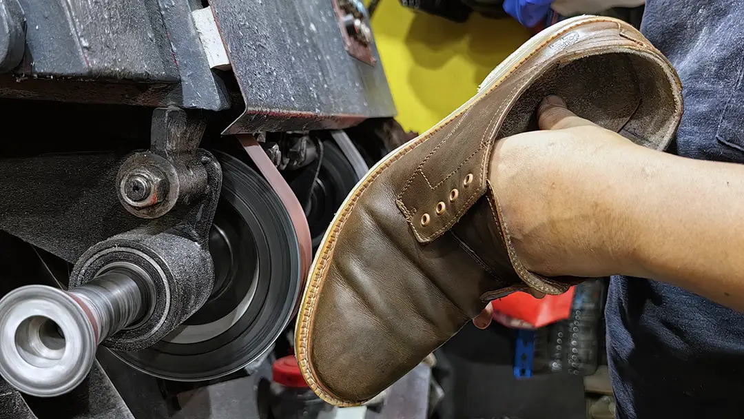 Leather boot being refinished on a polishing machine
