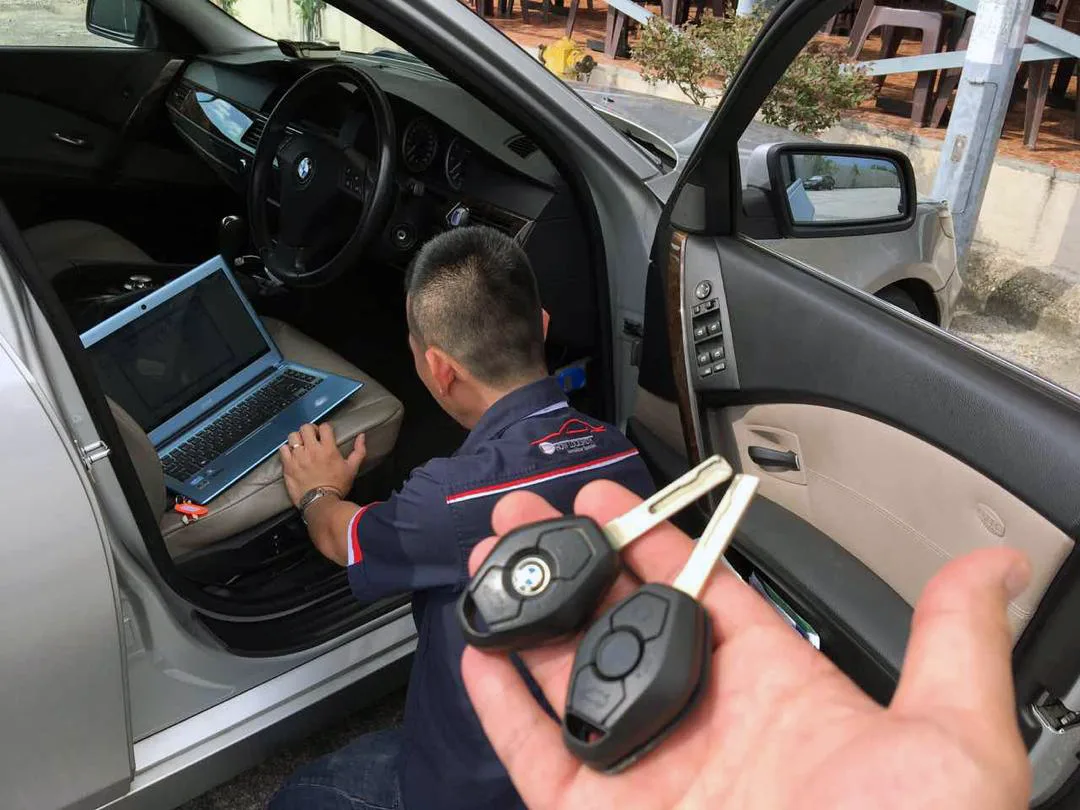 Technician programming a BMW key with a laptop inside the car